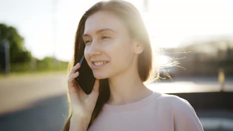 Mujer-Feliz-Hablando-Por-Teléfono-Móvil-Al-Aire-Libre,-Destellos-De-Lente-En-El-Fondo