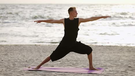 A-young-man-practices-yoga-while-standing-on-a-sports-mat-at-dawn.-Performing-a-specific-exercise.-Body-stretch.-Free-time,-rest