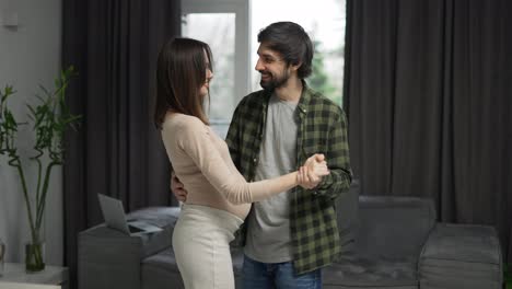 Carefree-pregnant-woman-dancing-with-loving-man-in-at-home