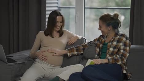 Woman-touching-pregnant-belly,-feeling-baby-movement,-friendship-closeness