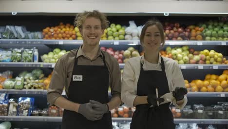 Happy-workers-in-black-apron-pose-for-the-camera-on-the-background-of-fruits.-Work-in-the-store.-Weekdays.-healthy-food