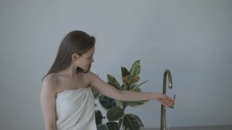 Woman-taking-a-bath-at-home-checking-temperature-touching-running-water-with-hand