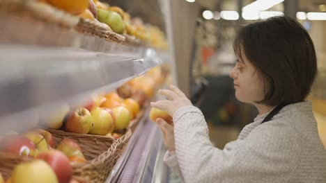 Woman-with-Down-syndrome-restocking-fresh-fruits-in-a-grocery-store,-side-view