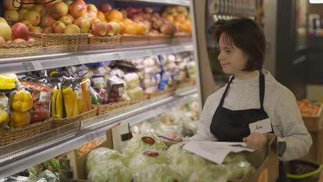 Woman-with-Down-syndrome-pushing-trolley-with-fresh-vegetables-to-restock-the-shelves