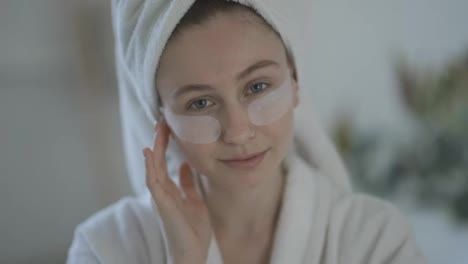 Portrait-of-a-woman-at-home-in-a-bathrobe-and-towel-and-patches-under-the-eyes