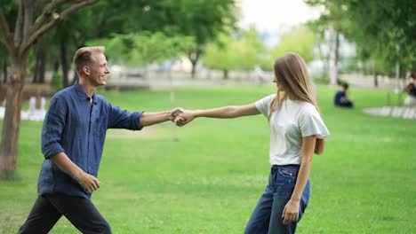 The-guy-dances-with-the-girl-in-the-park.-young-people-hold-hands-and-have-fun.-Happiness