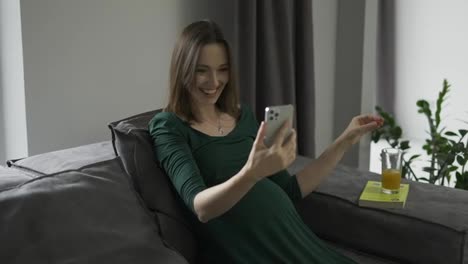 Pregnant-woman-video-chatting-on-mobile-phone-at-home,-slow-motion