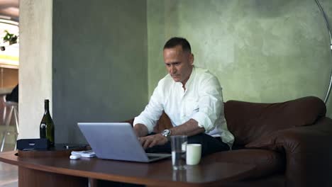 Businessman-working-on-laptop-computer-at-home-office.-Male-professional-typing-on-laptop-keyboard-at-office-workplace.-Portrait-of-positive-business-man-looking-at-laptop-screen-indoors