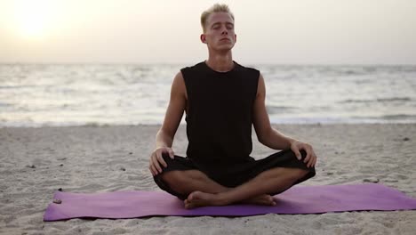 Ein-Junger-Mann-Macht-Yoga-Und-Meditiert-Auf-Einer-Sportmatte,-Während-Er-Im-Morgengrauen-Sitzt.-Eine-Bestimmte-Übung-Machen.-Meditation,-Hände.-Freizeit,-Erholung