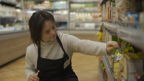 Woman-with-Down-syndrome-restocking-goods-in-a-grocery-store-on-lower-shelf