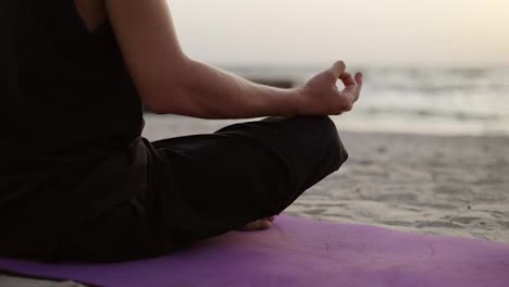 Ein-Junger-Mann-Praktiziert-Yoga-Und-Meditiert-Auf-Einer-Sportmatte,-Während-Er-Im-Morgengrauen-Sitzt.-Im-Hintergrund-Fliegt-Ein-Vogelschwarm.-Freizeit,-Ruhe