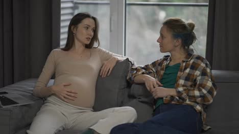 Woman-touching-pregnant-belly,-talking-about-pregnancy-with-friend