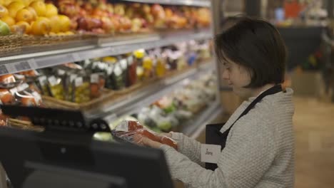 Worker-with-Down-syndrome-using-a-digital-tablet-in-the-fresh-produce-section-to-weight-the-goods