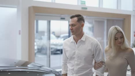 Man-with-sexy-blonde-woman-came-to-choose-car-in-dealership
