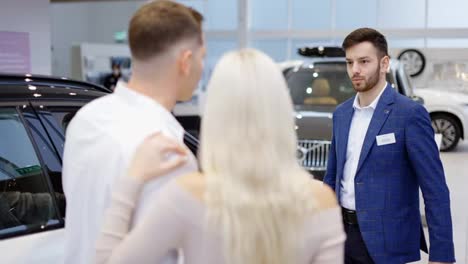 Footage-from-the-back---couple-talking-to-car-dealer-in-dealership-discussing-the-chosen-car