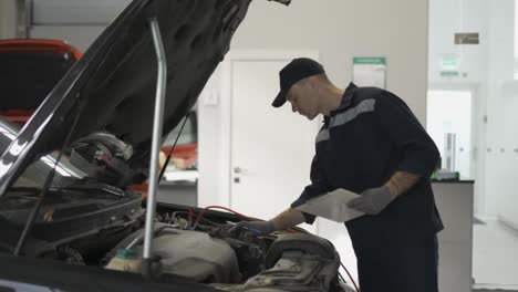 Mechaniker-In-Einer-Autoreparaturaufnahme,-Überprüfung-Des-Motors-Mithilfe-Eines-Tablets