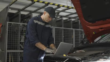 Auto-mechanic-uses-a-laptop-while-conducting-diagnostics-test