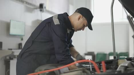 Car-mechanic-using-wrench-to-repair-the-engine-in-a-car-service