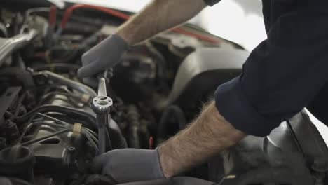 Car-mechanic-using-wrench-to-repair-the-engine-in-a-car-service,-close-up
