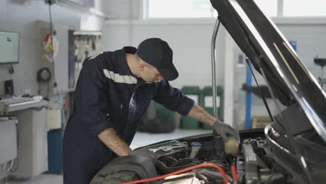 Mechanic-in-a-auto-repair-shop-checking-engine-manually
