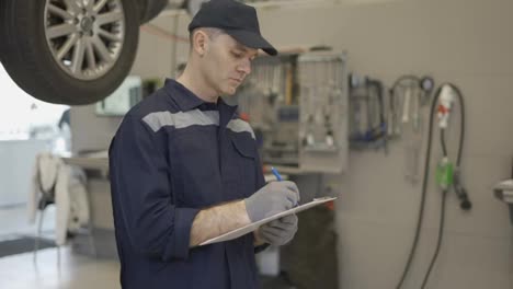 Mechanic-in-a-auto-repair-shop-making-notes-to-his-tablet