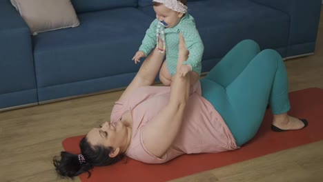 Plump-mother-holds-a-chubby-smiling-baby-in-her-arms-at-home-on-the-floor