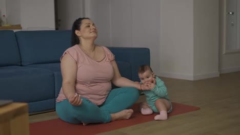 Plus-size-woman-disturbed-by-her-baby-while-sitting-on-the-floor-in-meditation,-slow-motion