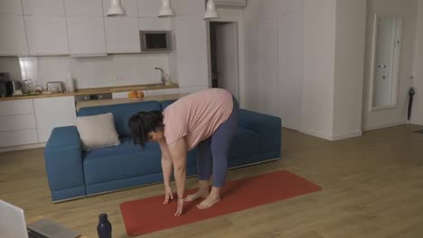 Overweight-woman-performing-yoga-asana-warrior-at-home
