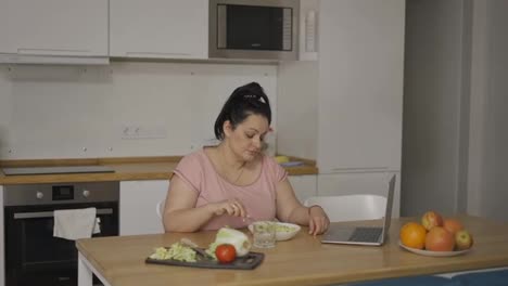 Mujer-Con-Sobrepeso-Comiendo-Cereales-Frente-A-La-Laptop