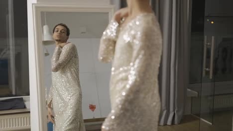 Sensual-man-in-a-dress-admires-himself-standing-in-front-the-mirror,-slow-motion