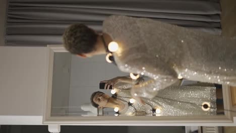 A-man-in-a-dress-posing-in-front-the-mirror-with-garland-on-neck,-sensually-moves
