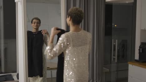 A-man-trying-his-new-black-dress-in-front-the-mirror-at-home