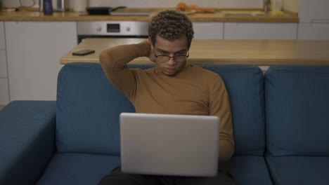 Overhelmed-young-man-using-laptop-on-the-sofa