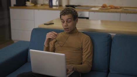 Diverse-ethnic-young-man-using-laptop-on-the-sofa-and-got-tired