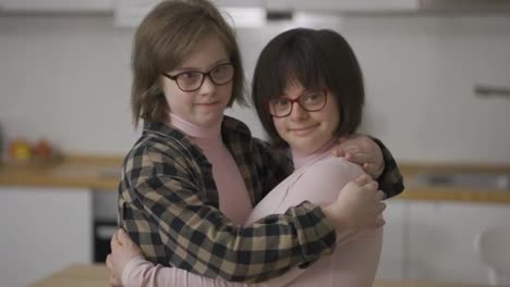 Two-happy-girls-with-down-syndrome-in-eyeglasses-standing-together-embracing