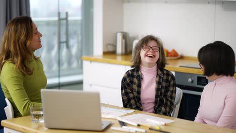 Teacher-teaches-young-girls-with-down-syndrome-using-laptop,-having-fun-together