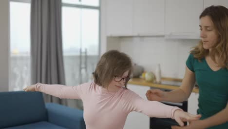 Positive-mature-woman-with-handicapped-daughter-learning-to-keep-balance-standing-on-yoga-mat