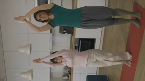 Positive-mature-woman-with-handicapped-daughter-practicing-yoga-at-home,-slow-motion