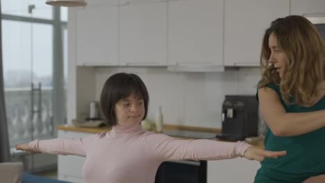 Girl-with-down-syndrome-practicing-yoga-position-at-home-with-help-of-teacher