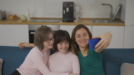 Mujer-Tomándose-Una-Selfie-Con-Sus-Hijas-Con-Síndrome-De-Down-Sentadas-En-El-Sofá-Del-Salón