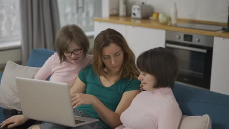 Happy-family-with-two-daughters-down-syndrome-sitting-on-sofa-have-fun-using-laptop