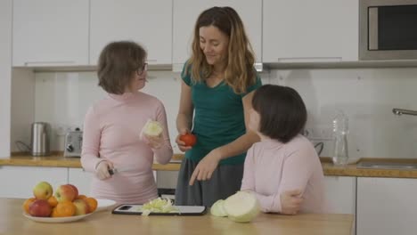 Two-girls-with-Down-Syndrome-are-learning-to-cook-with-their-mother-in-kitchen-at-home