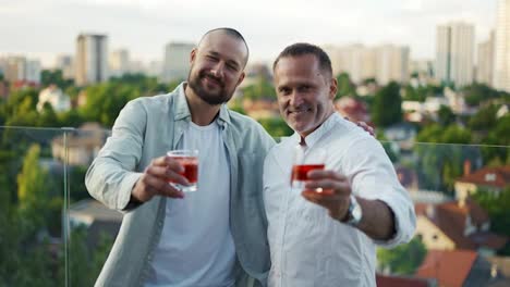 Two-happy-businessmen-are-holding-cocktails-and-posing.-Meeting-of-friends---businessmen.-Celebration-of-and-important-event