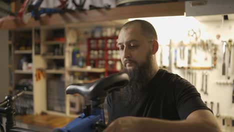 Handsome-bearded-master-repairing-a-bicycle-in-atmospheric-workshop