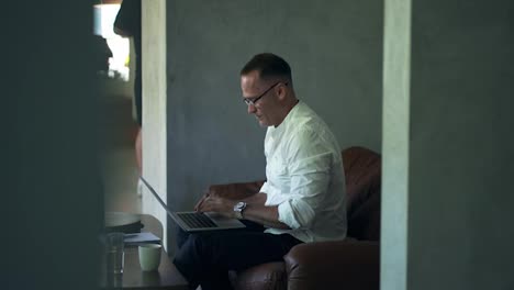 An-businessman-working-on-laptop-computer.-Male-professional-typing-on-laptop-keyboard-at-caffe.-Portrait-of-positive-business-man-looking-at-laptop-screen-indoors