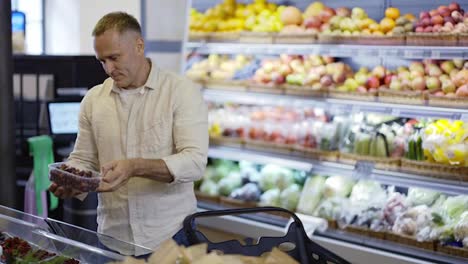 A-middle-aged-shop-visitor-selects-a-product-in-a-grocery-store-and-stores-it-in-plastic-containers.-Going-to-the-grocery-store.-Healthy-lifestyle