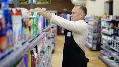 A-middle-aged-store-worker-arranges-goods-on-a-shelf.-Work-in-the-store.-Control-the-product.-Happiness
