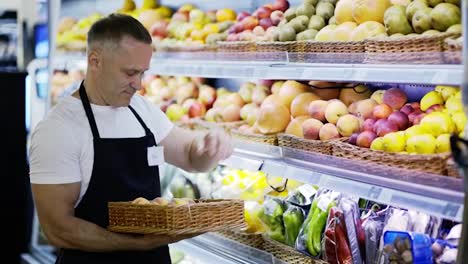 A-happy-middle-aged-worker-in-a-grocery-store-arranges-goods-on-the-shelves.-Goods-control.-The-concept-of-working-in-a-grocery-store