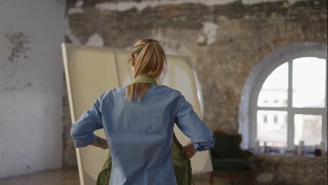 Unrecognizable-woman-put-on-apron-to-start-painting-in-workshop