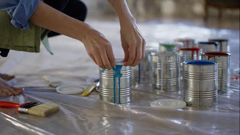 Female-hands-in-studio-workshop-open-different-colors-of-paint-in-jar,-prepare-supplies
